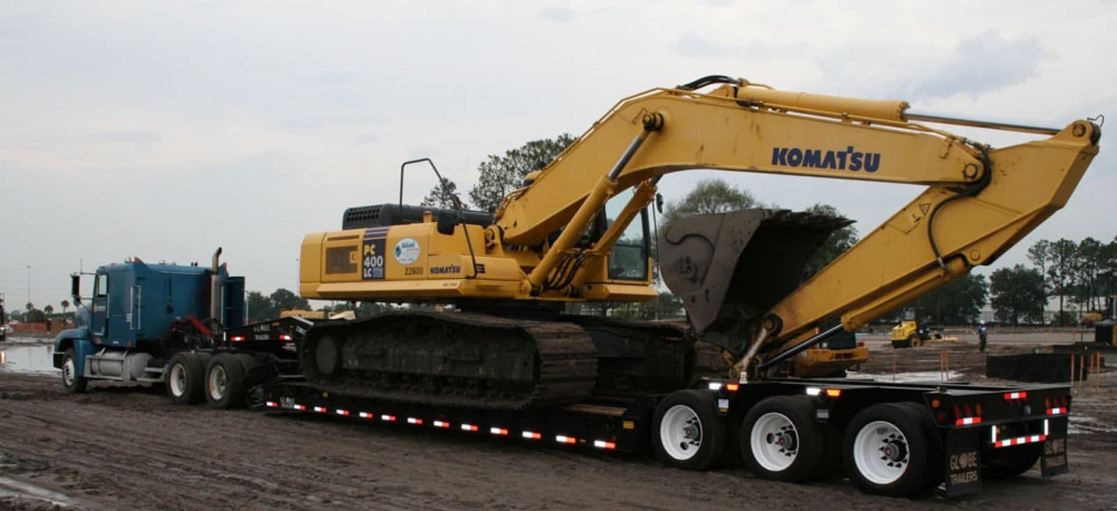 Yellow Komatsu excavator loaded on a removable-gooseneck (RGN) lowboy trailer