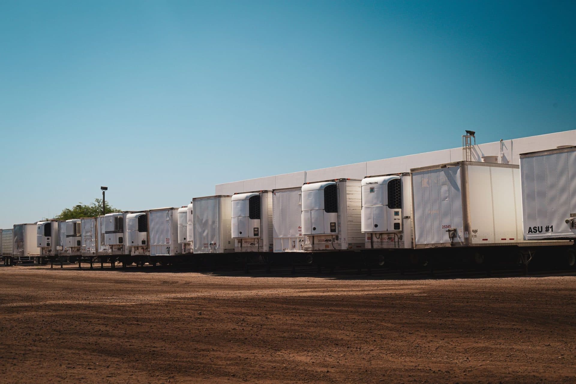 Long row of refrigerated trailers with front-mounted cooling units parked in a lot