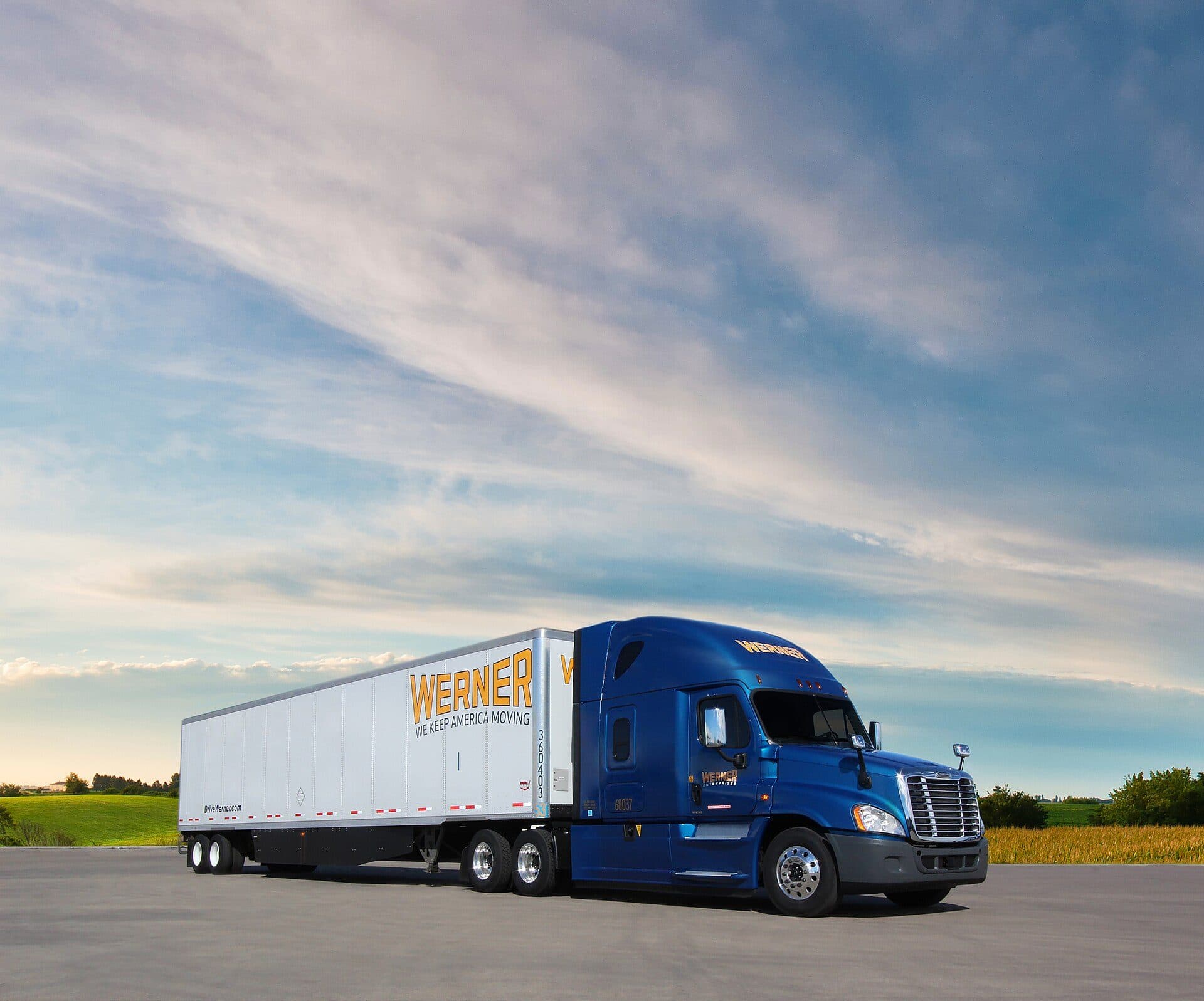 Blue Freightliner Cascadia pulling a Werner dry van under a wide sky
