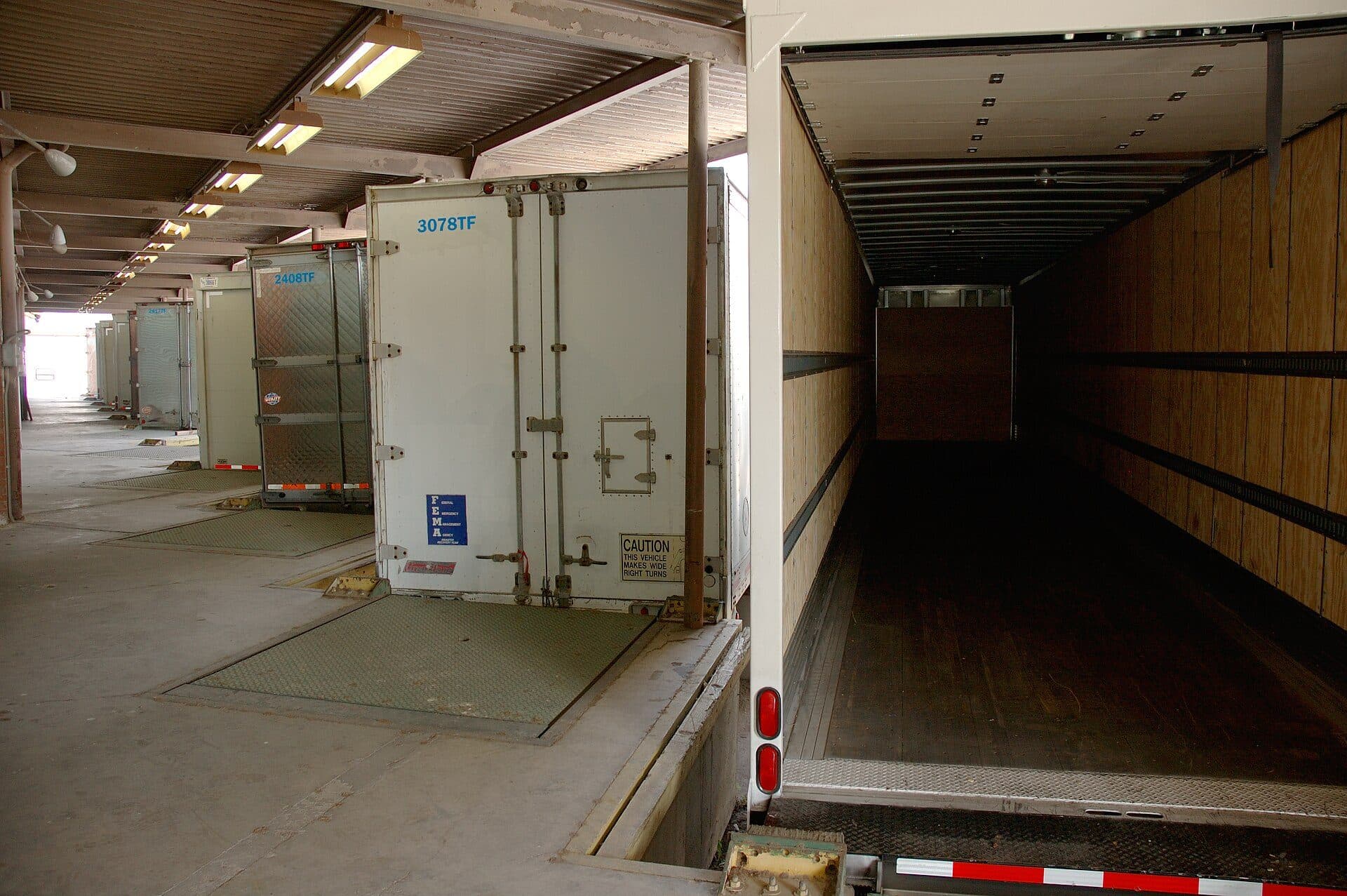 Open dry van trailer at a dock door showing the empty wood-lined interior