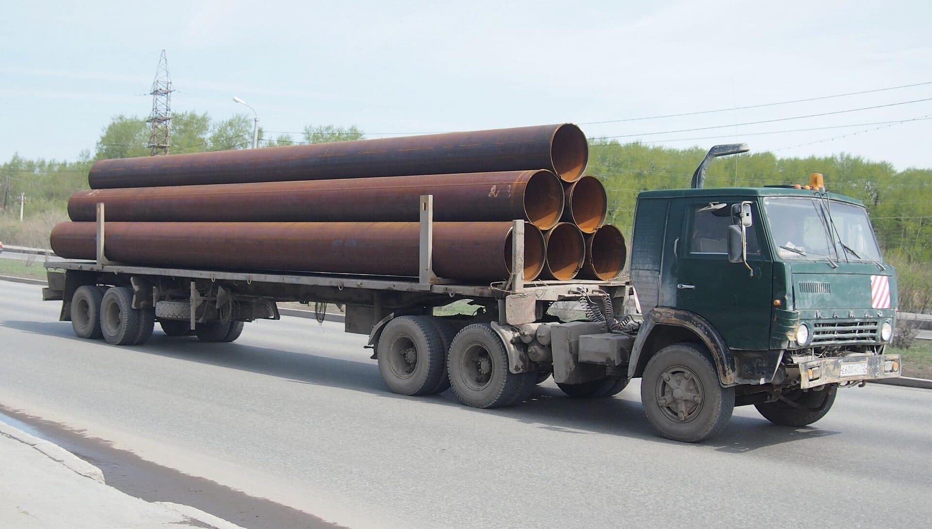 Large steel pipes loaded on a flatbed trailer on a highway