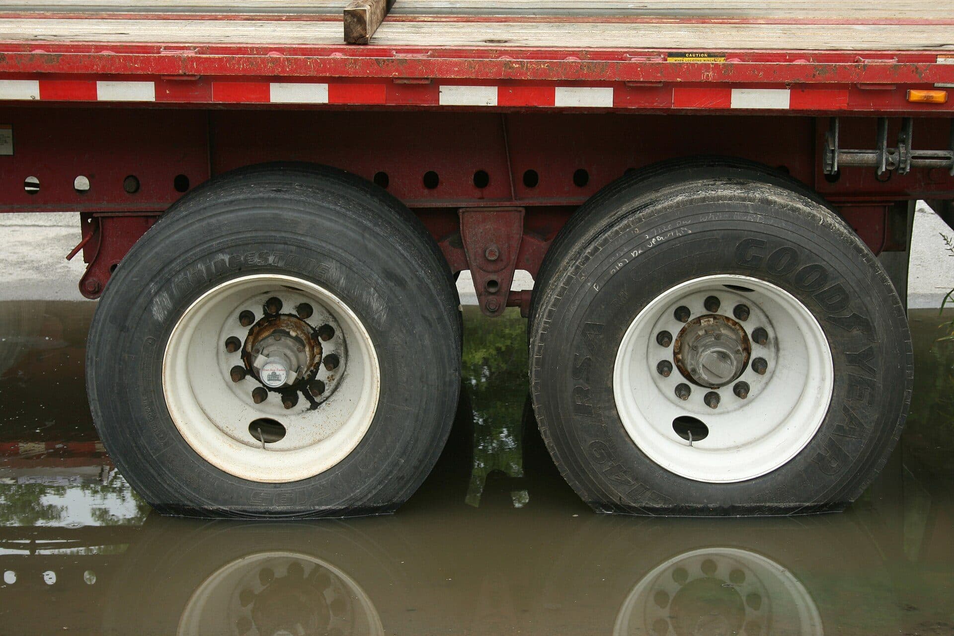 Close-up of a flatbed trailer's tandem wheels and rub rail