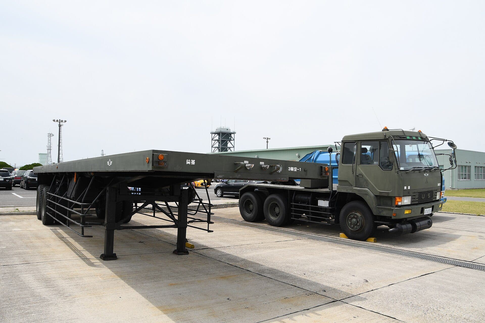 Empty flatbed semi-trailer coupled to a truck in an industrial lot