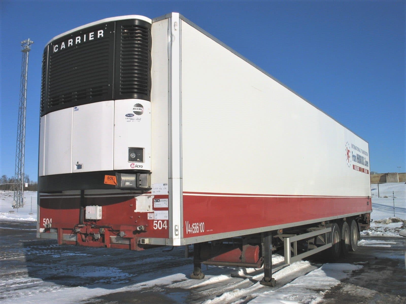 Front of a refrigerated trailer showing a Carrier cooling unit and red skirt